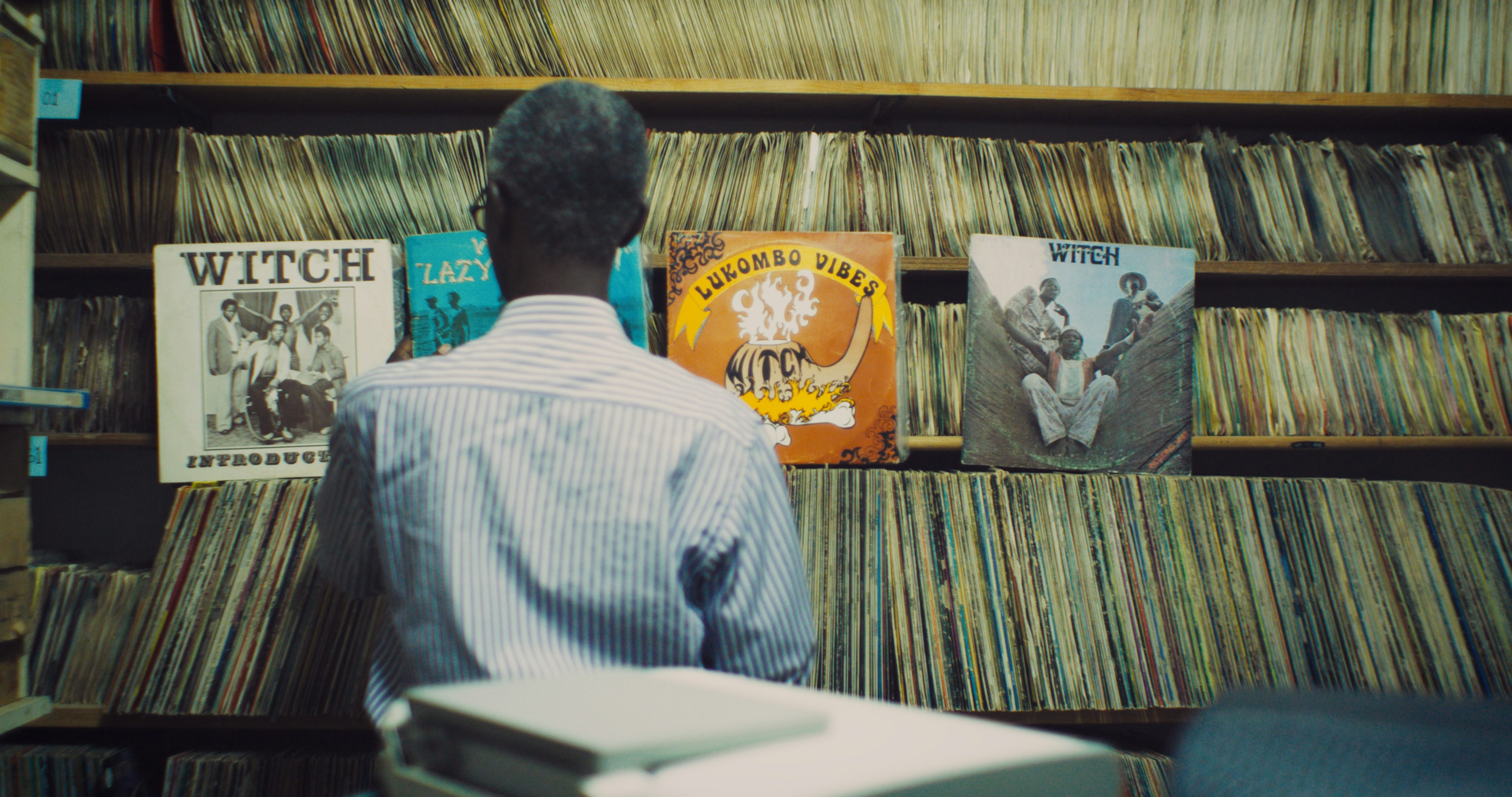 a man looking at a wall of records and 4 WITCH albums